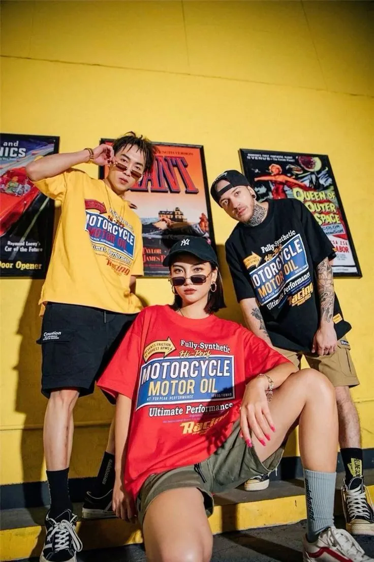 three models wearing oversized motor cycle graphic t shirts posing in a yellow retro themed room