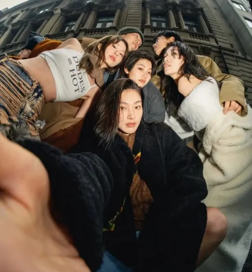 Gen Z group in trendy outfits taking a low angle selfie